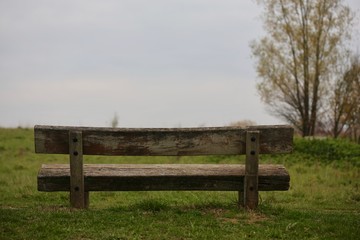 Fototapeta na wymiar Holzbank zum ausruhen für Picknick vor Wiese mit viel Horizont