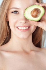 Young beautiful girl smiling with avocado close-up