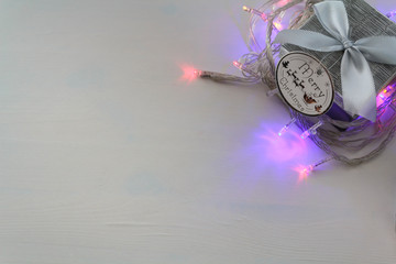 Christmas Gift box and Christmas lights on white table. Top view and copy space