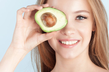 Young beautiful girl smiling with avocado close-up