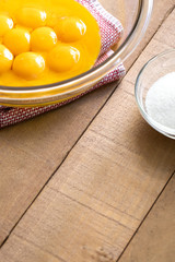 Bowl of egg yolks beside a sugar dish, with space for text on bottom