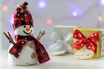 Snowman with gift boxes and christmas lights on the background