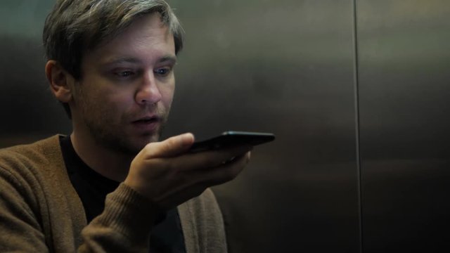 A businessman talking on the phone at the elevator student tourist man freelancer voice recognition ai speech audio message helper