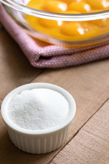 Fototapeta na wymiar Ramekin of sugar with a glass bowl of egg yolks