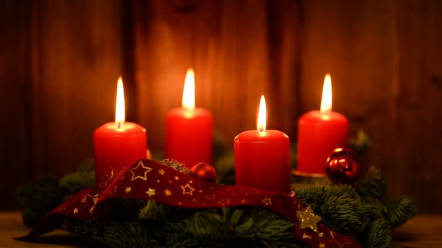 Adventskranz mit 4 brennenden roten Kerzen Holzhintergrund