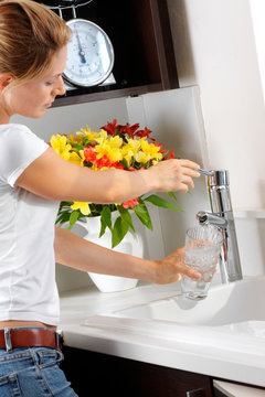 WOMAN POURING GLASS OF TAP WATER