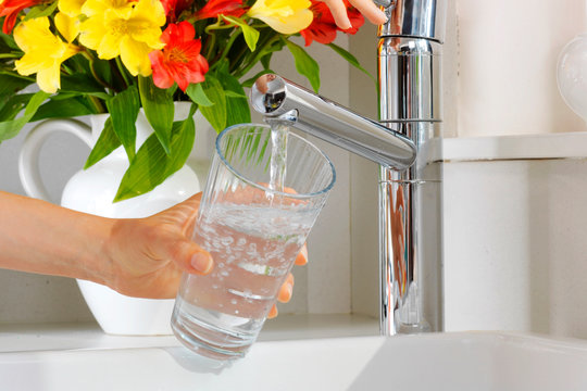 WOMAN POURING GLASS OF TAP WATER