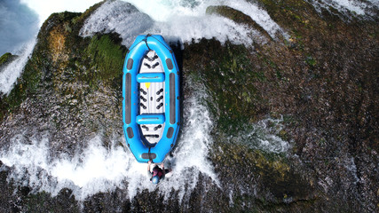 group of people doing white water rafting activity on wild river with waterfall