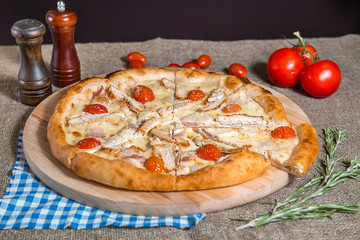 homemade pizza with cheese, tomato, bacon, ham on sackcloth background