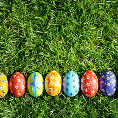 Easter eggs lying on green spring grass arranged in one lane. Space for text