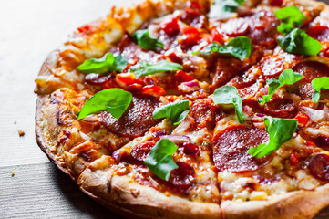 sliced Pepperoni Pizza with Mozzarella cheese, salami, chorizo, tomato sauce, pepper, Spices and Fresh arugula. Italian pizza on wooden table background