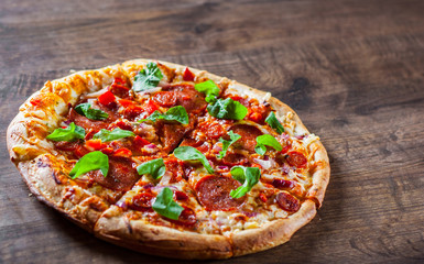 sliced Pepperoni Pizza with Mozzarella cheese, salami, chorizo, tomato sauce, pepper, Spices and Fresh arugula. Italian pizza on wooden table background