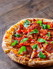 sliced Pepperoni Pizza with Mozzarella cheese, salami, chorizo, tomato sauce, pepper, Spices and Fresh arugula. Italian pizza on wooden table background