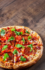 sliced Pepperoni Pizza with Mozzarella cheese, salami, chorizo, tomato sauce, pepper, Spices and Fresh arugula. Italian pizza on wooden table background