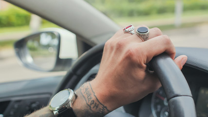A man with rings on his hand drives a car. Hand close-up.