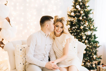 Portrait of a beautiful young family against the backdrop of the Christmas tree. Attractive family celebrates New year and smiles