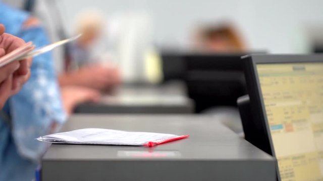 airport employee checking passport of people passengers on border and selling tickets in airport counters. check-in on board aircraft, close up, close-up, Checking passports at the airport check in.