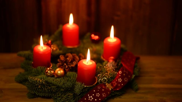 adventskranz mit 4 brennenden kerzen auf altem Holz