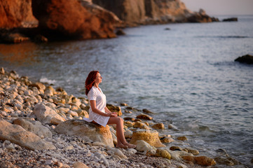 Beautiful woman walking along the coast of the sea at sunset