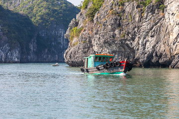 Ha Long Bay, Vietnam-December 20, 2013. Vietnamese fishing boat full of fish and fisherman fishing on small bamboo boat on December 20, 2013 in Ha Long Bay in northeast Vietnam.