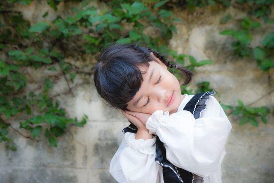 Portrait of Asian cute girl acting as sleeping on her hand. relaxing and kid dreaming concept.
