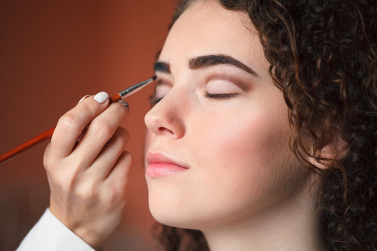 Closeup portrait of beautiful woman getting professional make-up with brush. Beauty and makeup concept