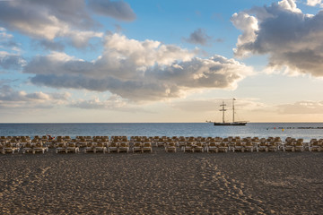 beach with sun beds and ocean background and sailing boat  