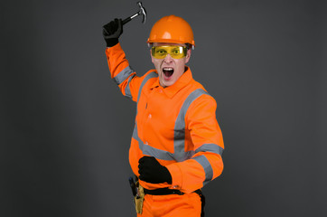 Angry and annoyed builder worker with hammer is shaking by his fist and shouting. A foreman...