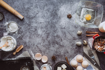 Healthy baking ingredients. Spoon with flour, dishes, eggs, butter salt and rolling pin on a grey background.Bakery background frame. Top view, copy space.