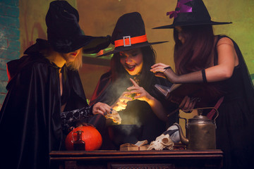 Image of three witches in hats with book of potions making potions in cauldron
