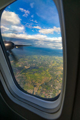 Aerial view from airplane window. Aircraft flying above land with beautiful clouds in the blue sky background. Aviation concept. Tourism,Journey,Travel concept.