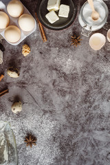 Healthy baking ingredients. Spoon with flour, dishes, eggs, butter salt and rolling pin on a grey background.Bakery background frame. Top view, copy space.