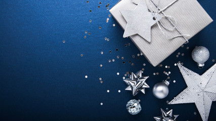 Merry Christmas and Happy Holidays greeting card, frame, banner. New Year. Noel. Silver Christmas gifts, ornaments on blue background top view. Winter holiday xmas theme. Flat lay.