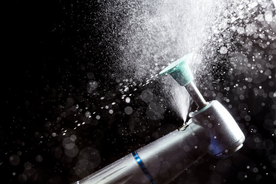 Dental tip with polishing head and splashes of water on dark background.