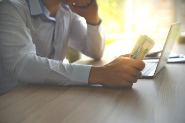Businessman sitting on the desk and holding money in the hand. business profit,investment and budget concept