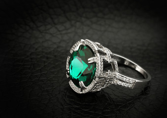 jewelry ring with big green gem on black leather background © dimj