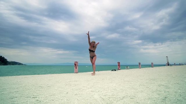 Beautiful girl having fun doing gymnastic at beach pier, SLOW MOTION