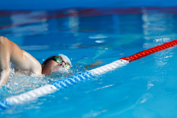 Photo of sports man in blue cap swimming in pool