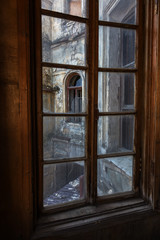 Broken glass in the windows of an old abandoned mystical house. A horror picture of broken window glass. Gloomy interior, depressive background for the design of tragedy, horror, Halloween