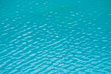 Amazing textured background of calm azure clean water surface. Sunshine in mountain lake close up. Beautiful ripples on shiny water in sunny day. Wonderful relax texture.