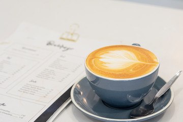 Cup of coffee latte in coffee shop. Young Barista man making a cup of latte art.