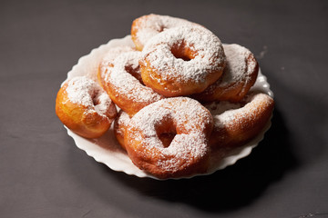 doughnuts sprinkled with powdered sugar on a white plate, selective focus