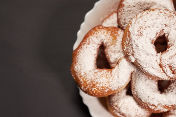 Fototapeta na wymiar doughnuts sprinkled with powdered sugar on a white plate, selective focus