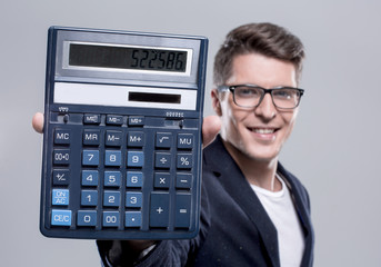 cheerful young handsome man looking at camera and holding calcul