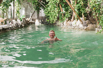 Happy boy in the pool showing thumb up