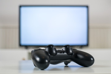 Video game controller in front of blurred TV background - Gaming concept