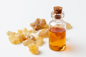 A bottle of frankincense essential oil with frankincense resin on a white background