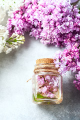 Glass jar with aroma oil and with lilac flowers for spa and aromatherapy. Spa concept.