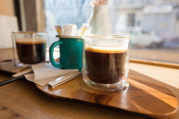Morning cup of delicious flavored Americano on a wooden table near the panoramic window