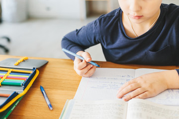 Naklejka premium Schoolboy doing his homework on desk at home.